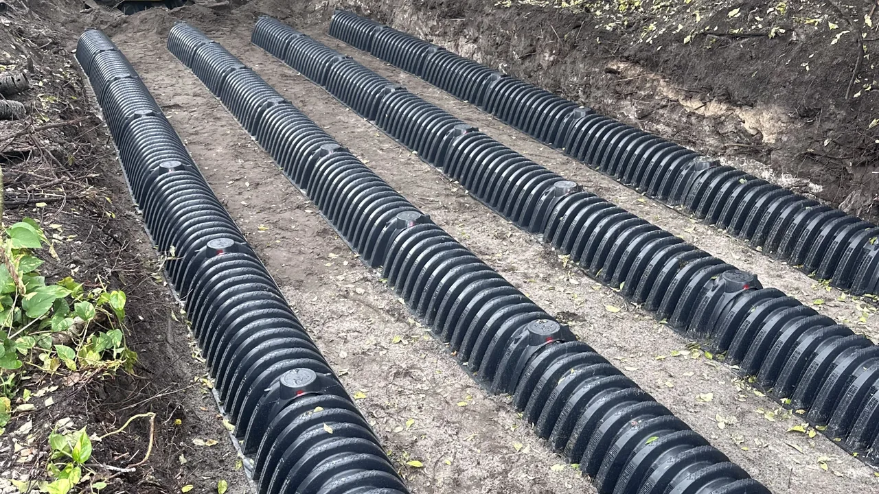 Septic drain field chambers running along a dug trench under trees, septic system installation