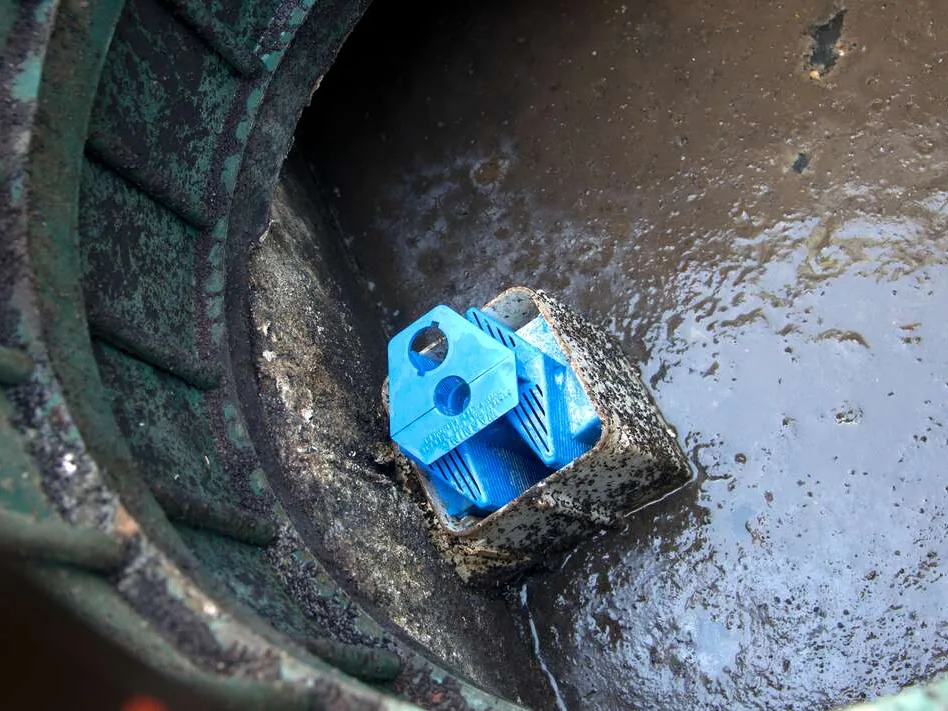 Blue effluent filter seated in its housing inside a septic tank, seen through an open green riser, septic tank filters