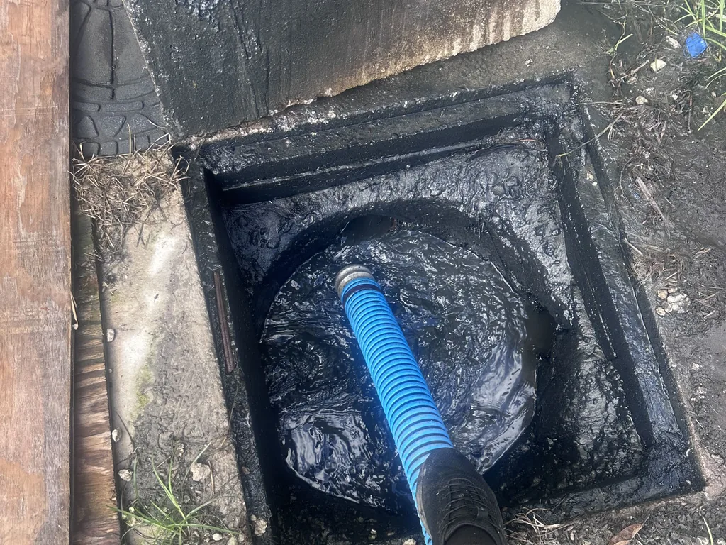 Open concrete septic tank lid with a vacuum hose running into the tank, septic tank lids and risers